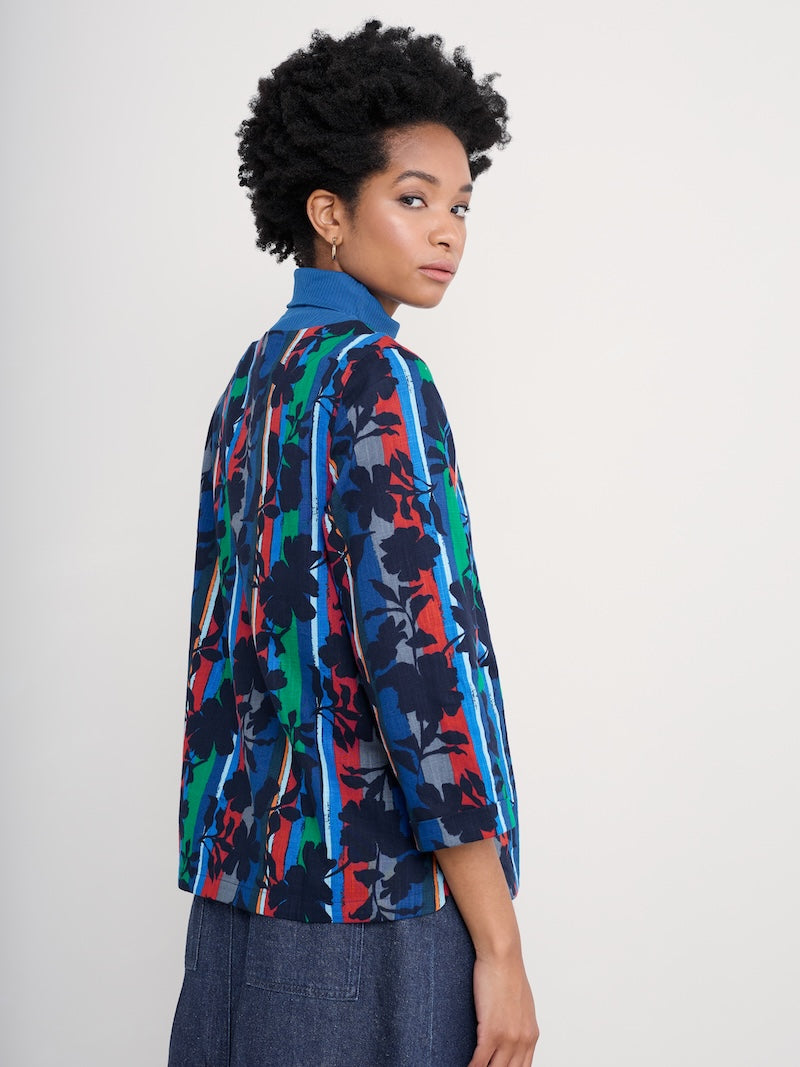 Person wearing a colourful patterned top on a plain background