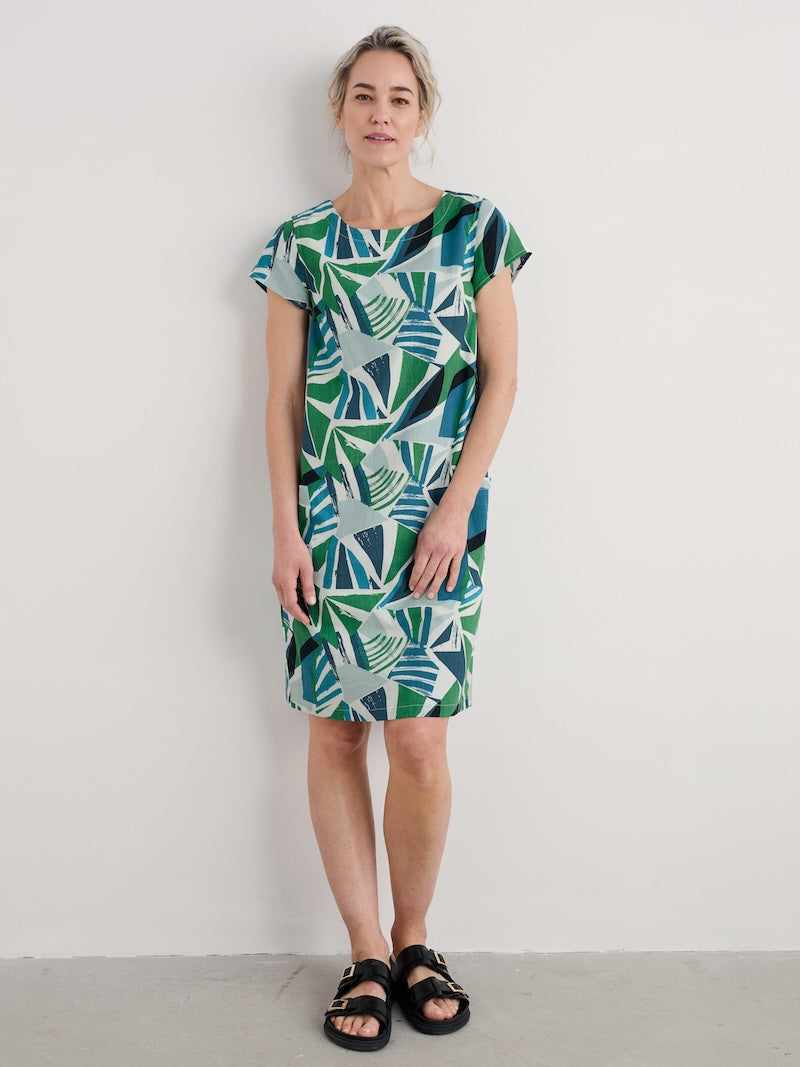 Woman wearing a green and blue patterned dress against a white background