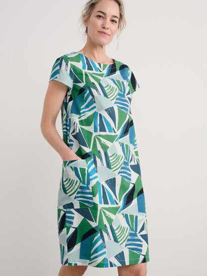 Woman wearing a green and blue patterned dress on a plain background