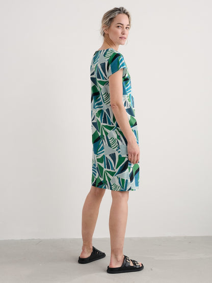 Woman wearing a green and blue patterned dress against a white background