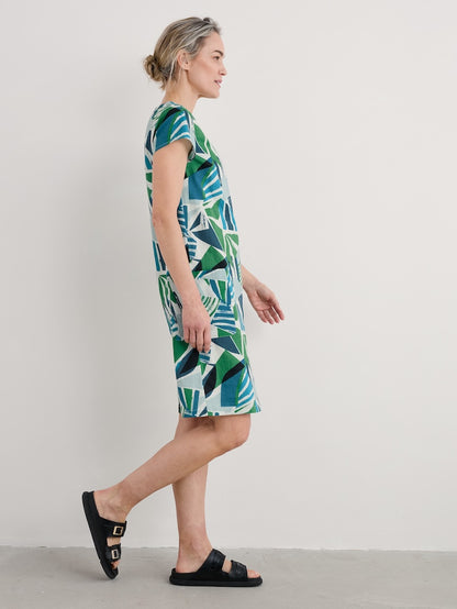 Woman wearing a green and white patterned dress on a plain background