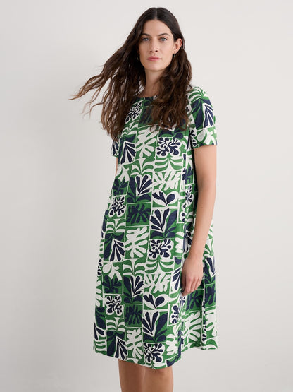 Woman wearing a green and white patterned dress on a plain background