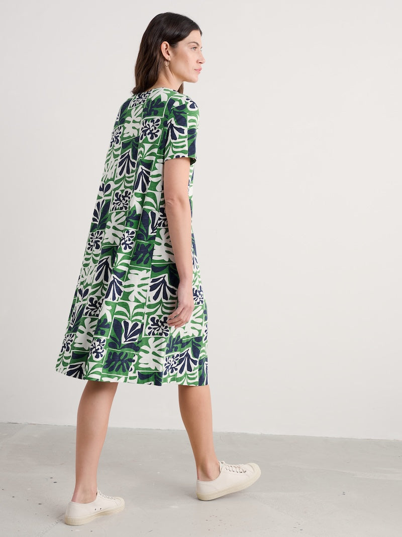 Woman wearing a green and white patterned dress on a plain background