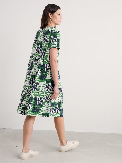 Woman wearing a green and white patterned dress on a plain background