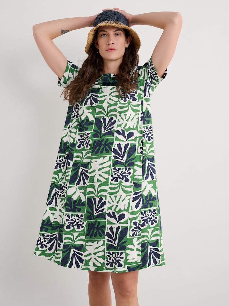 Woman wearing a green and white patterned dress with a plain background