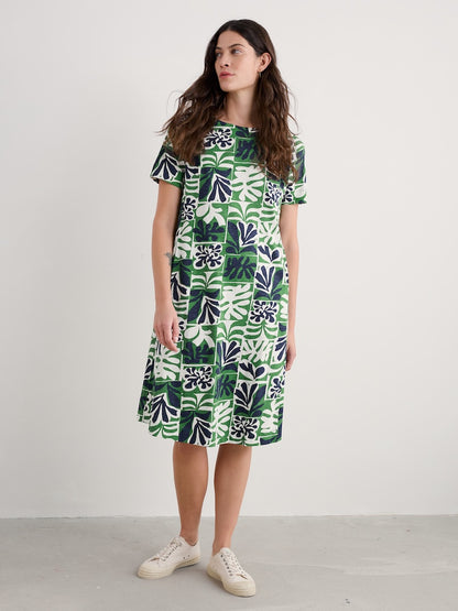 Woman wearing a green and white patterned dress against a plain background