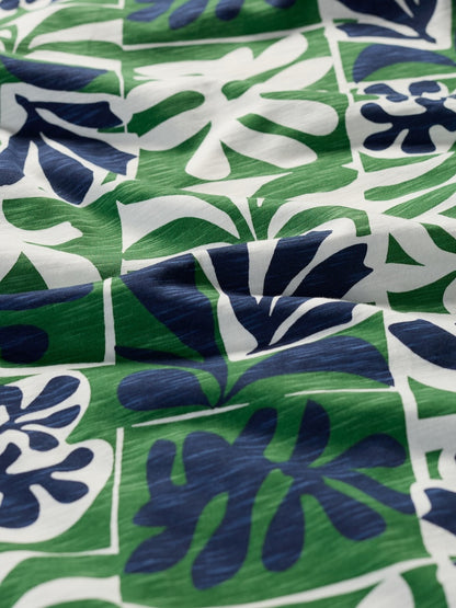 Close-up of fabric with a tropical leaf pattern in green, blue, and white.