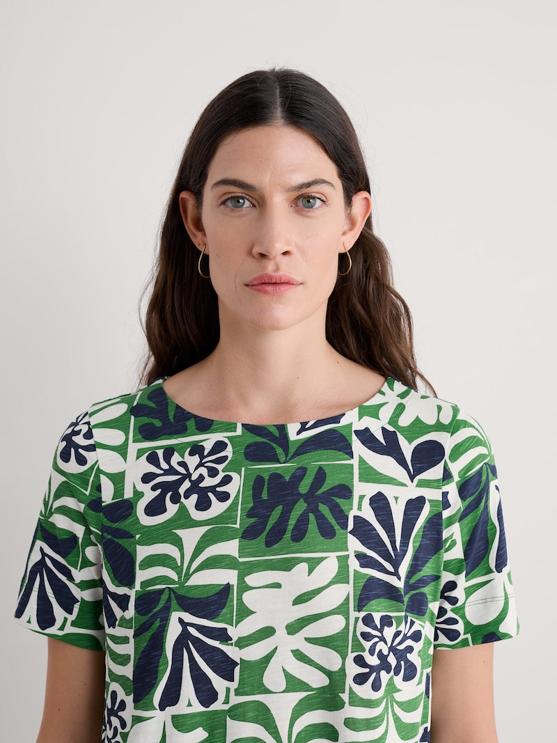 Woman wearing a green and white patterned dress against a plain background