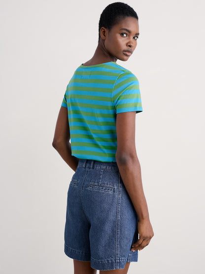 Woman wearing a green and blue striped shirt with denim shorts on a white background