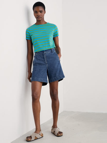 Woman wearing a green and blue striped shirt and denim shorts on a white background