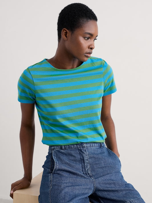 Person wearing a blue and green striped shirt with jeans on a neutral background