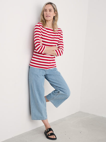 Woman wearing a red and white striped shirt and blue jeans against a white background