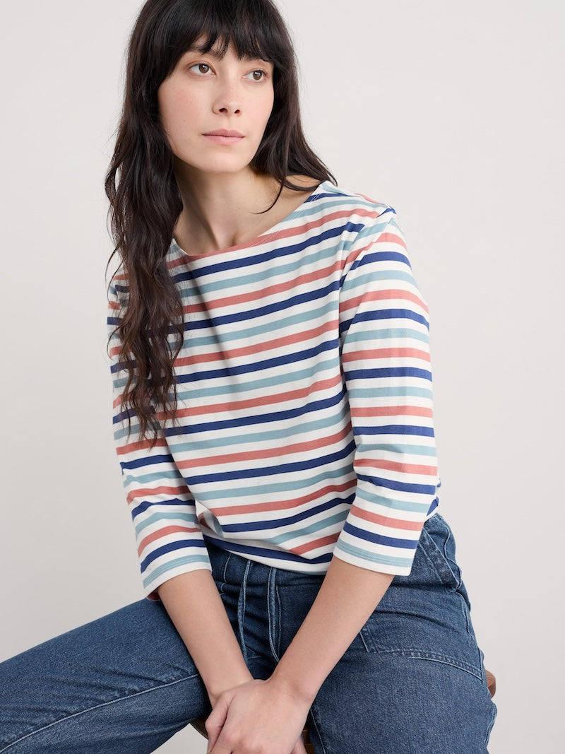 Woman wearing a striped shirt and jeans against a plain background