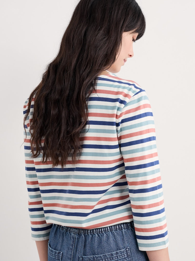 Woman wearing a striped long-sleeve shirt with a plain background