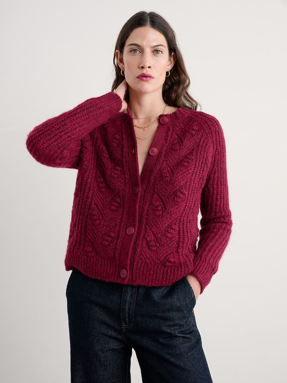 Woman wearing a red knitted cardigan against a plain background