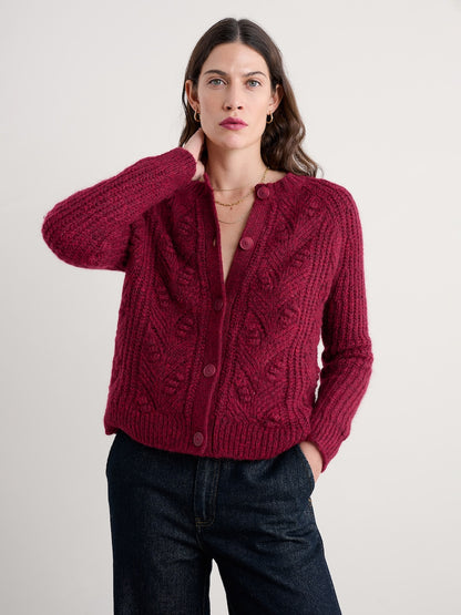 Woman wearing a red knitted cardigan against a plain background