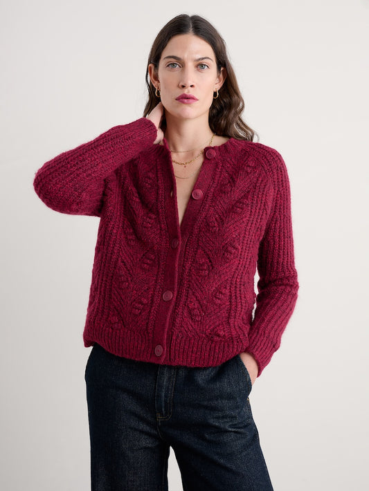 Woman wearing a red knitted cardigan against a plain background