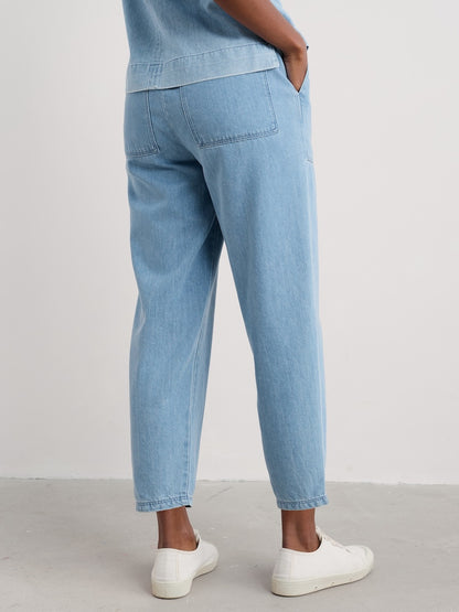 Woman wearing light blue jeans and white shoes on a plain background