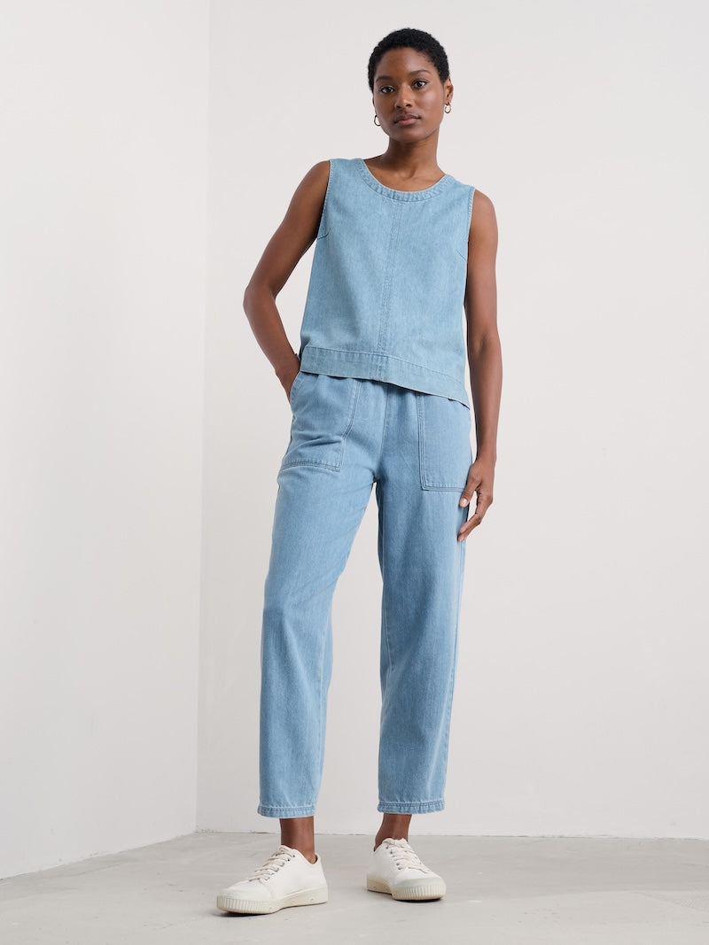 Woman wearing a light blue sleeveless top and pants set on a white background