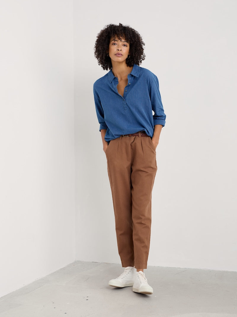 Person wearing a blue shirt and brown pants against a white background