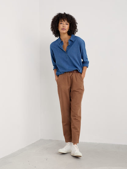 Person wearing a blue shirt and brown pants against a white background