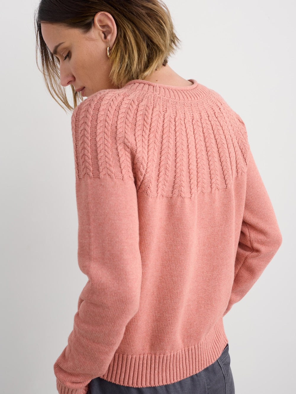 Person wearing a pink knitted sweater on a plain background