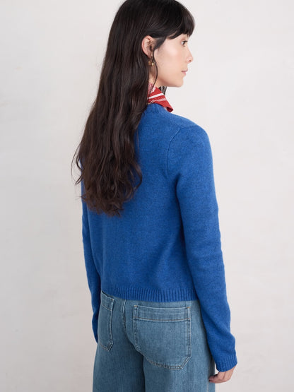 Person wearing a blue sweater and red scarf on a plain background