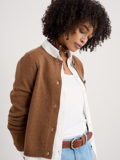 Woman wearing a brown cardigan over a white shirt with a plain background