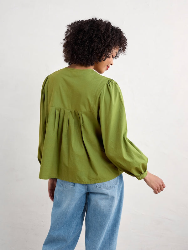 Woman wearing a green blouse and blue jeans on a white background