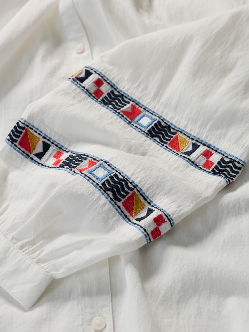 Close-up of a white shirt with colorful embroidery on the collar.