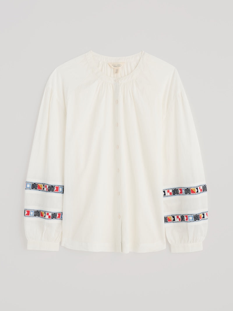 White long-sleeve shirt with colourful patterns on sleeves against a light grey background
