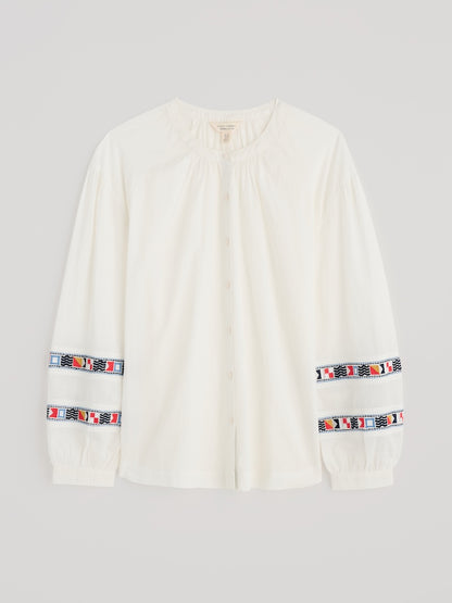 White long-sleeve shirt with colourful patterns on sleeves against a light grey background