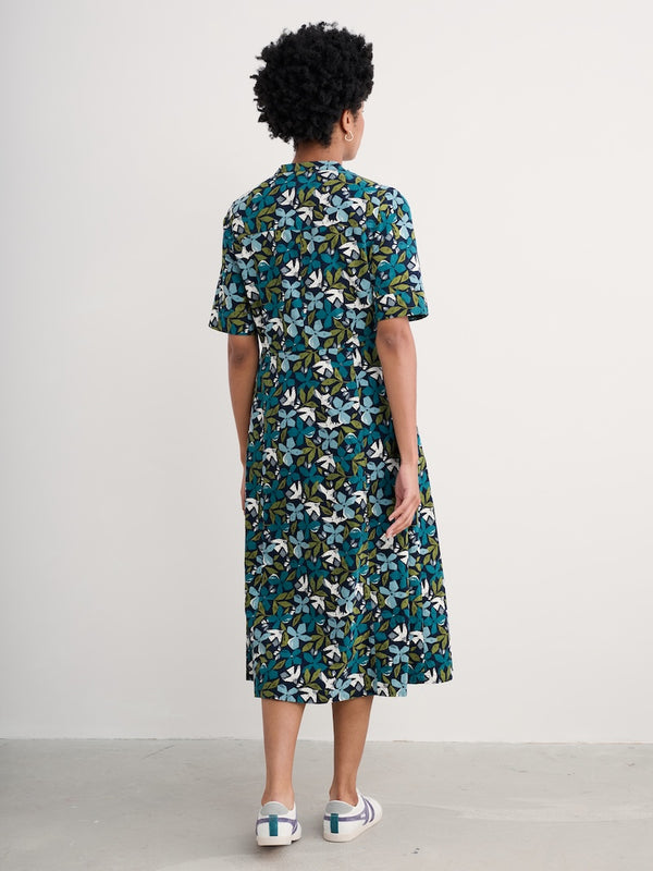 Woman wearing a organic cotton denim floral dress with a white background