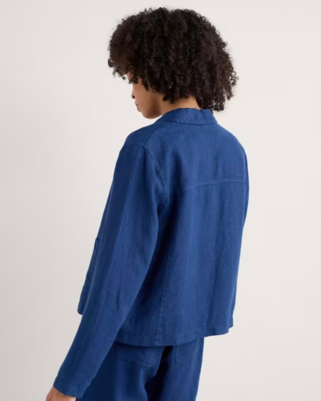 Woman wearing a blue linen jacket on a white background