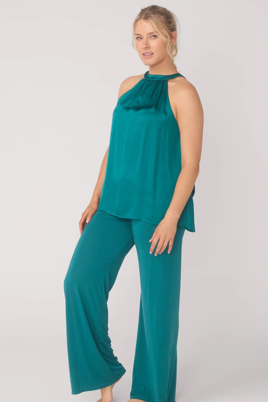 Woman wearing a teal top and pants on a white background