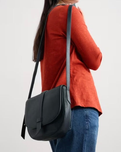 Person wearing a navy shoulder bag on a plain background