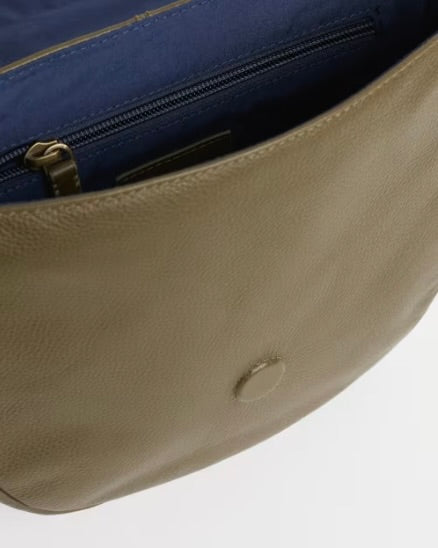 Close-up of a green leather bag with a blue fabric background
