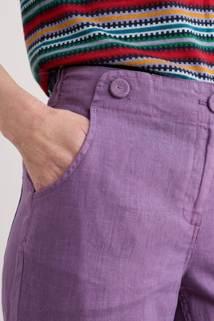 Purple pants with a colourful striped shirt worn by a woman.