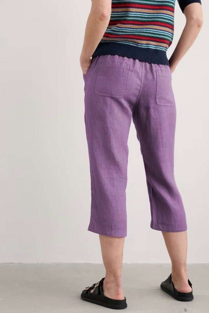 Woman wearing purple pants and a striped shirt on a plain background