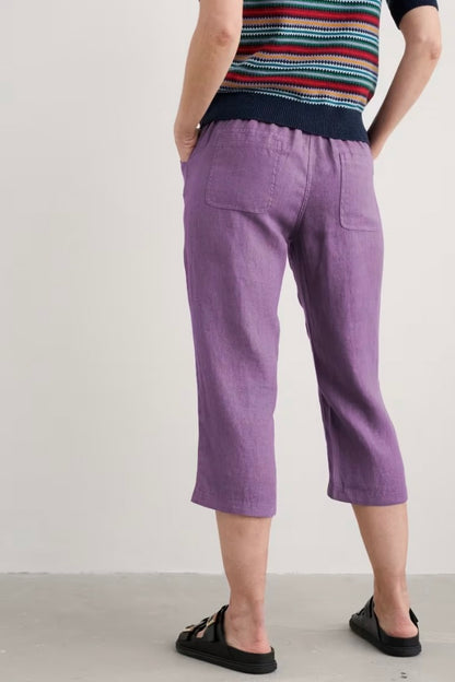 Woman wearing purple pants and a striped shirt on a plain background