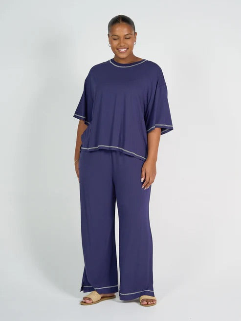Woman wearing a navy blue bamboo shirt and pant set on a white background