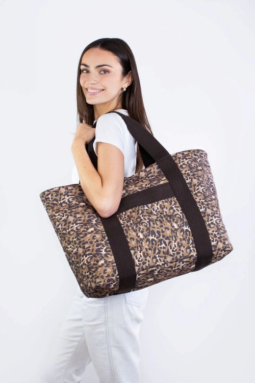 Woman holding a leopard print tote bag against a white background