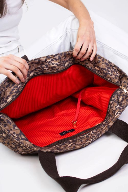 Leopard print bag with red interior on a white background