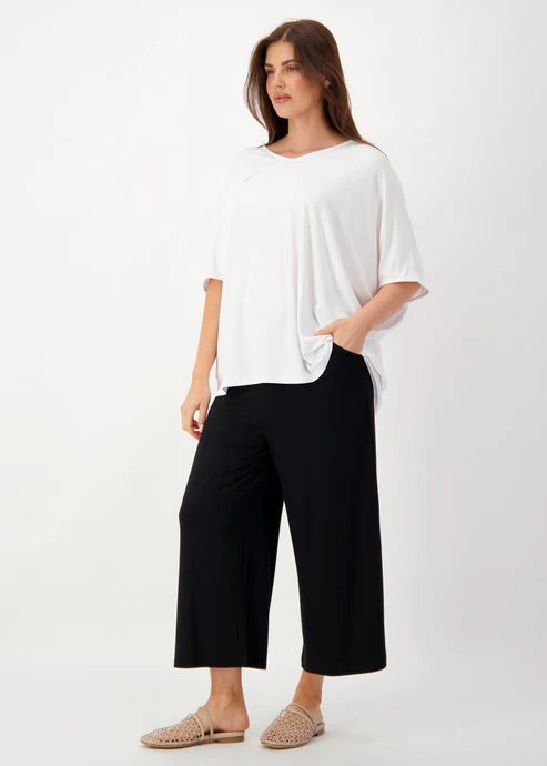 Woman wearing a white bamboo top and black bamboo cropped pants on a white background