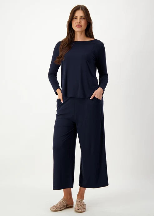 Woman wearing a navy blue long sleeve bamboo top with wide-leg bamboo pants on a white background