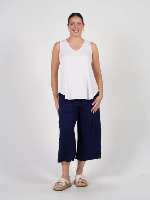 Woman wearing a white sleeveless bamboo top and navy blue bamboo pants on a white background