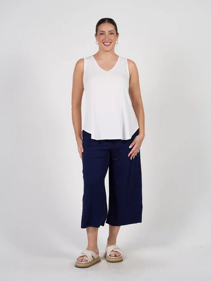 Woman wearing a white sleeveless bamboo top and navy blue bamboo pants on a white background