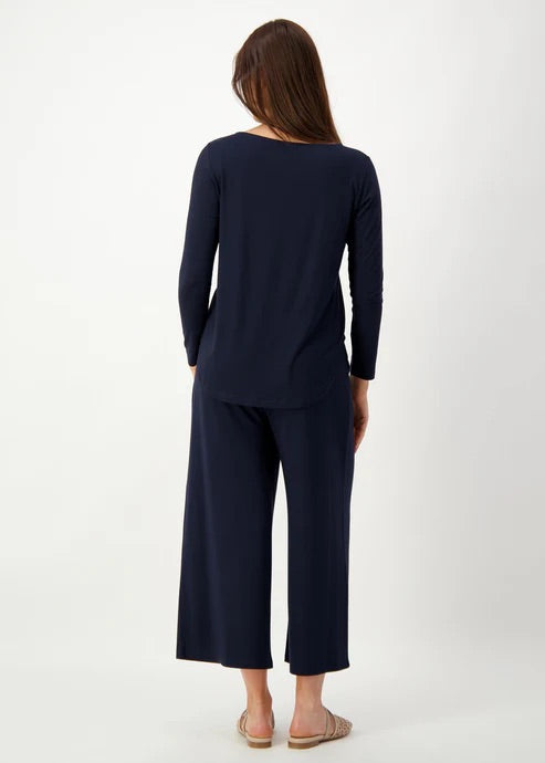 Woman wearing a navy blue bamboo long sleeve top with wide-leg bamboo pants on a white background