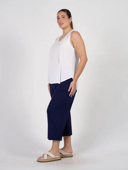 Woman wearing a white sleeveless bamboo top and navy blue bamboo pants on a white background