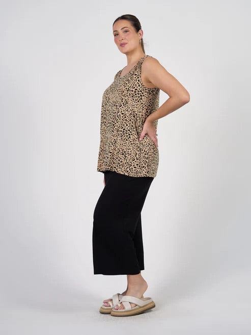 Woman wearing a leopard print top and black bamboo pants on a white background